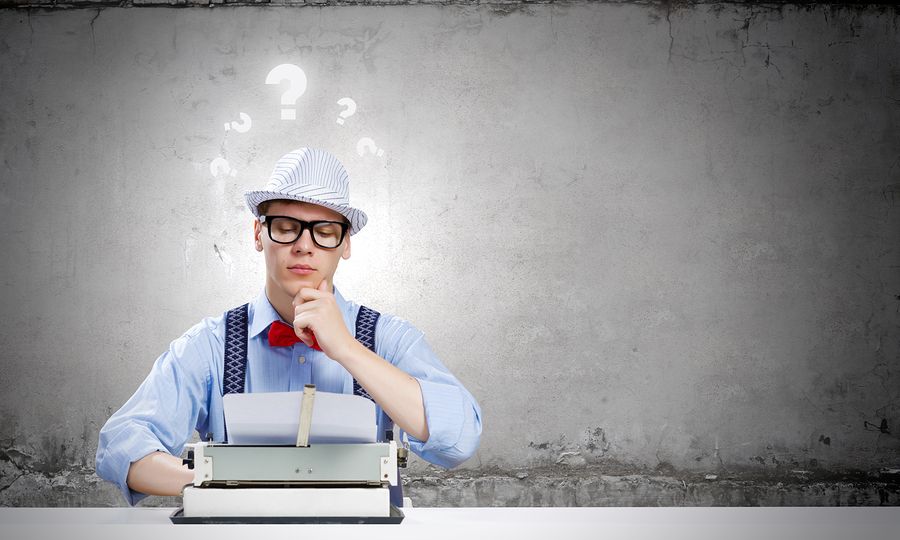 Young funny man in glasses writing on typewriter